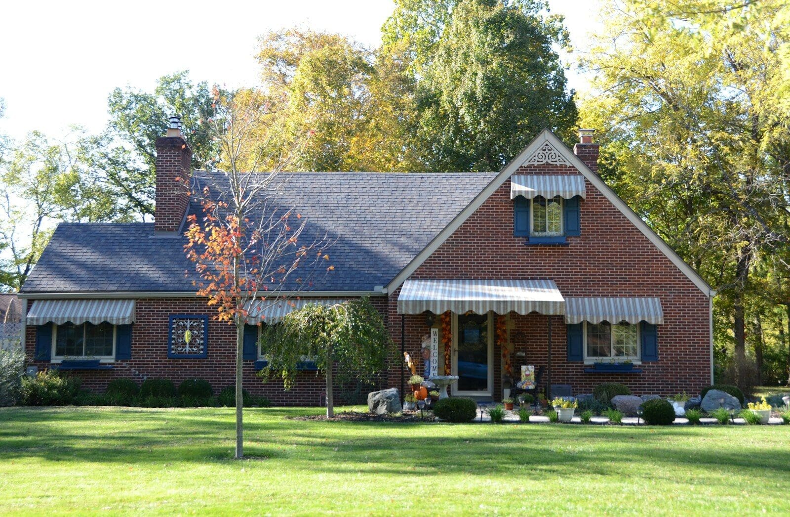 A brick house with a green lawn and trees